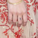 Minka Monroe tattoo - Letter X on her right hand middle finger