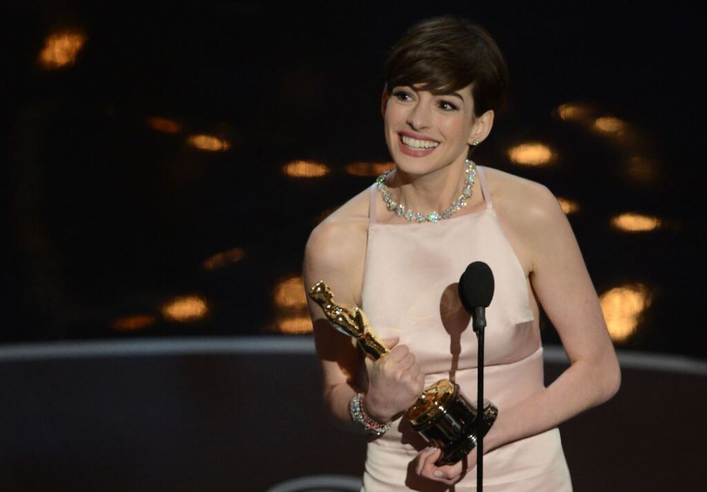 Anne Hathaway celebrating her Oscar win for Les Misérables, a major milestone in her $80 million wealth journey
